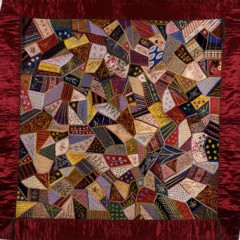 Multi-coloured patchwork quilt with a red border.